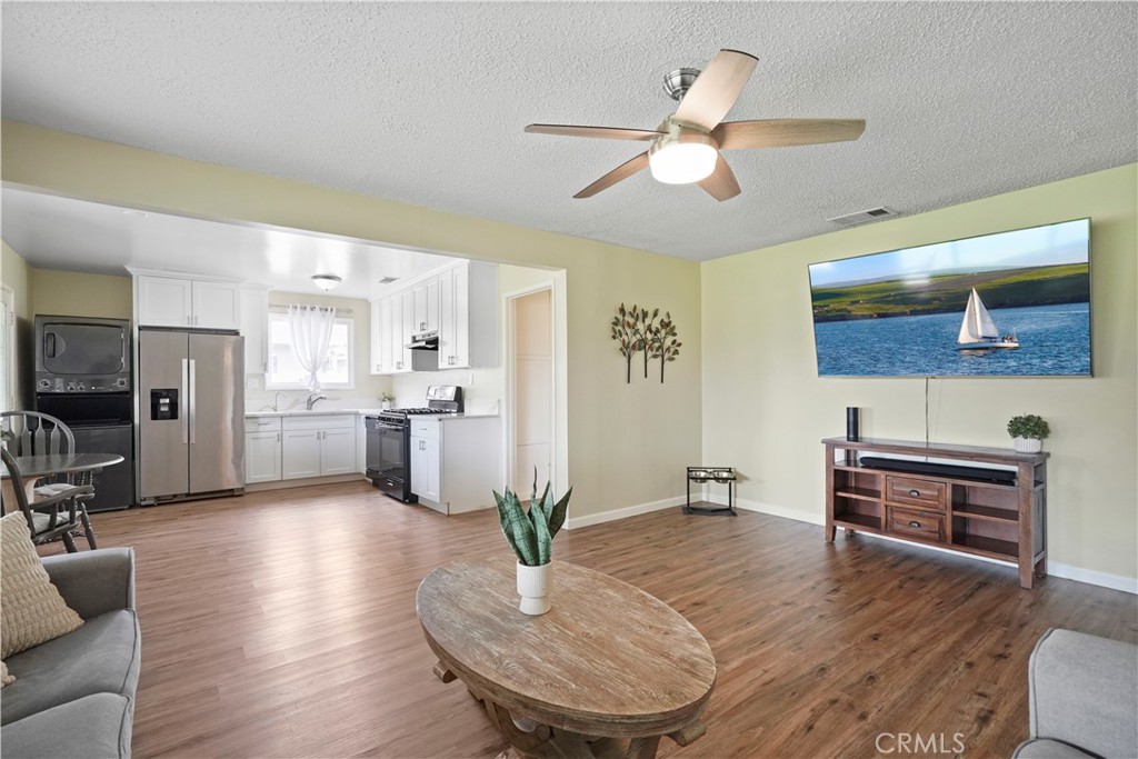 a living room with furniture kitchen view and a wooden floor