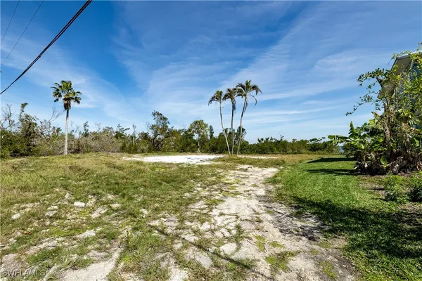 a view of a big house with a big yard and large trees