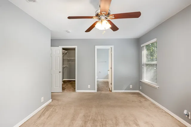 an empty room with windows and fan
