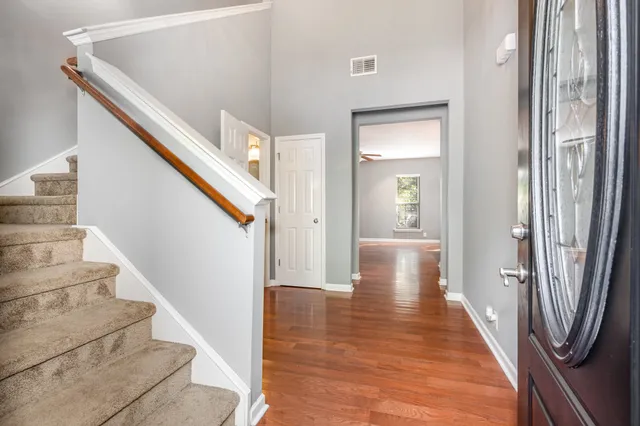 a view of a hallway with wooden floor and staircase