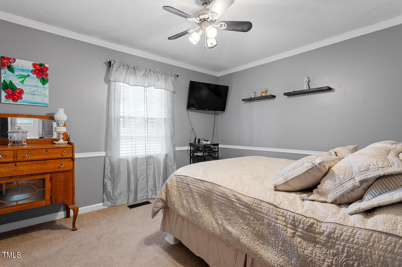 1660 Benson Road Angier, NC 27501 - Photo 24 of 32 a bedroom with a bed and a tv