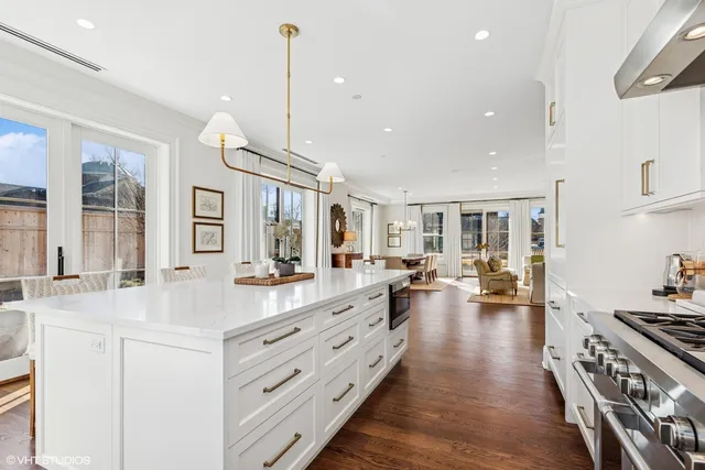 a large white kitchen with a large window a sink and stainless steel appliances