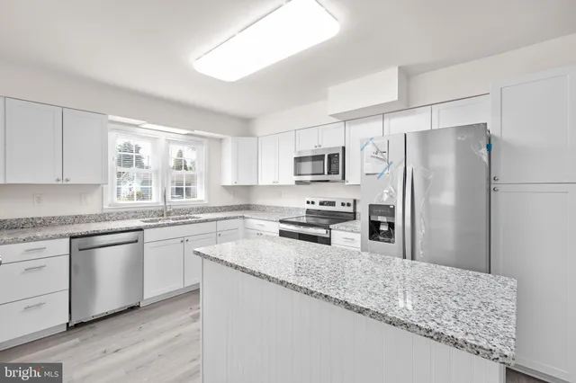 a kitchen with granite countertop a refrigerator sink and microwave