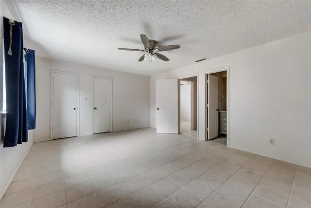an empty room with a chandelier fan and windows