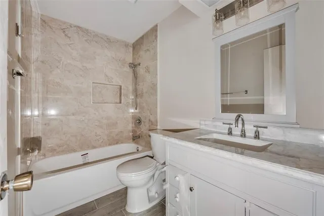 a bathroom with a granite countertop toilet sink and mirror