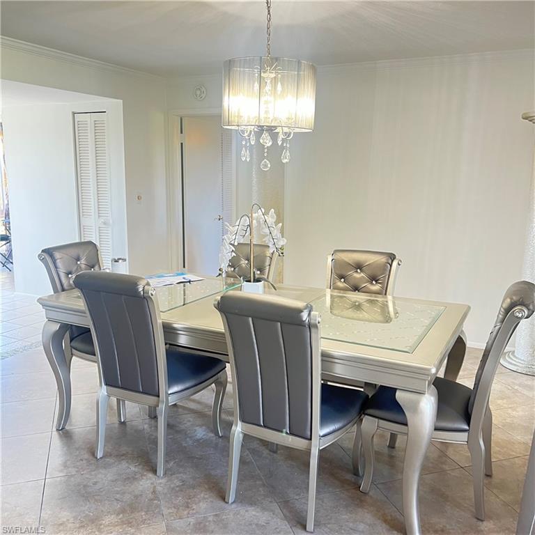 197 Harrison Road, Unit 3 Naples, FL 34112 - Photo 7 of 14 Dining room with light tile patterned floors, a chandelier, and crown molding