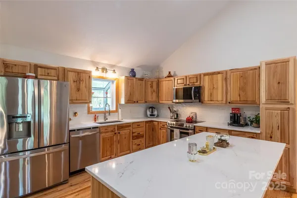 a kitchen with stainless steel appliances granite countertop a sink a stove and a refrigerator with wooden floor