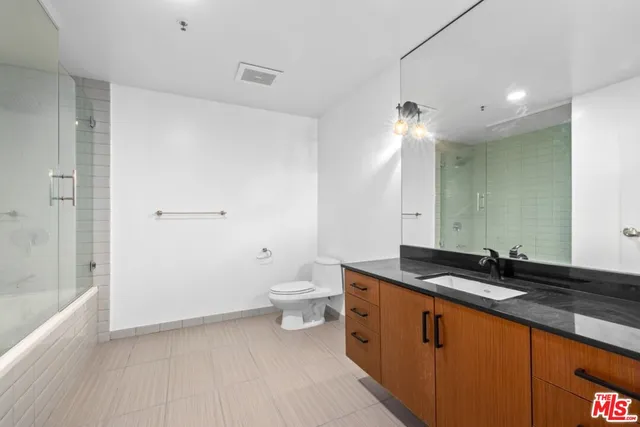 a spacious bathroom with a granite countertop sink a toilet and shower