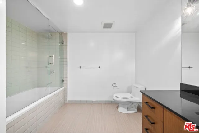 a bathroom with a granite countertop sink a toilet and shower