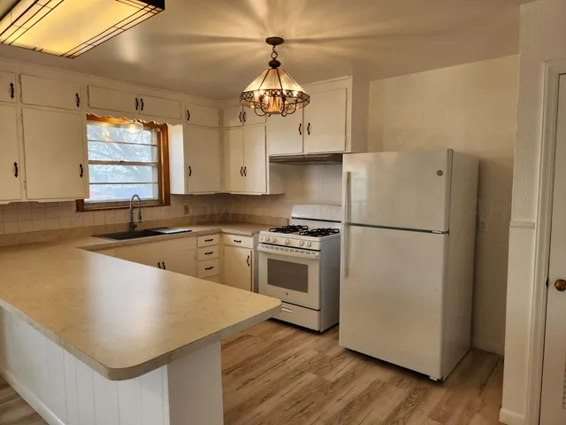 a kitchen with stainless steel appliances granite countertop a sink a stove a refrigerator and island with wooden floor