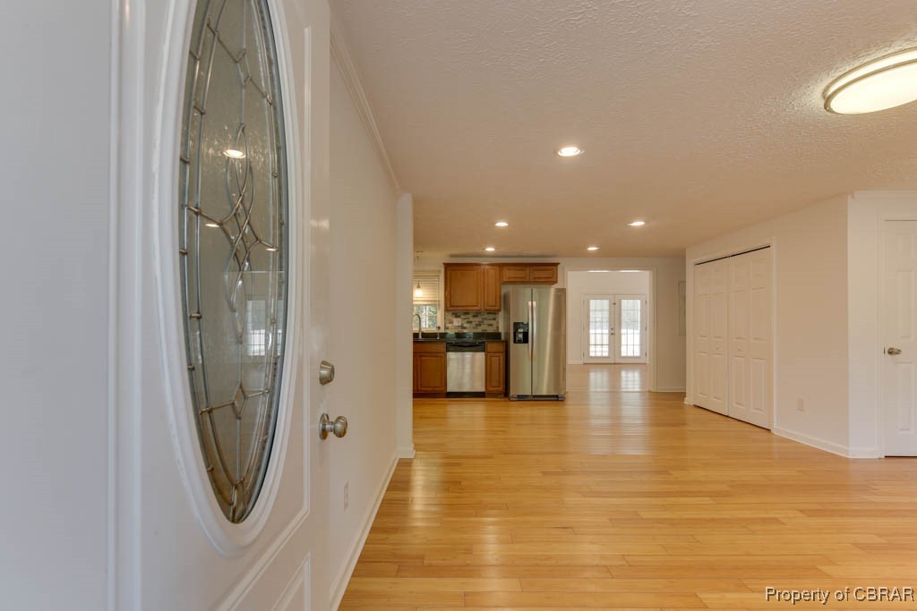 8729 Marlfield Road Gloucester, VA 23061 - Photo 5 of 32 Hallway featuring light hardwood / wood-style flooring, a textured ceiling, french doors, and crown molding