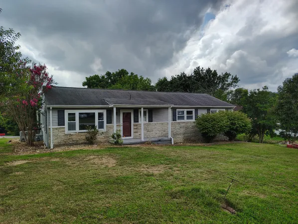 a front view of a house with a garden and trees