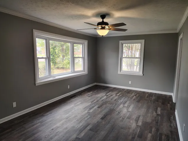 a view of an empty room with a window and wooden floor
