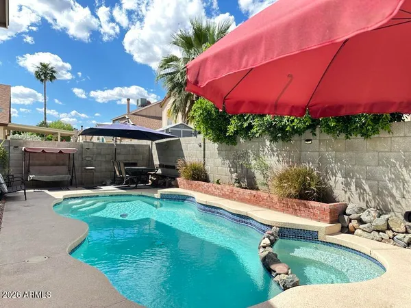 a view of a swimming pool with a table and chairs under an umbrella