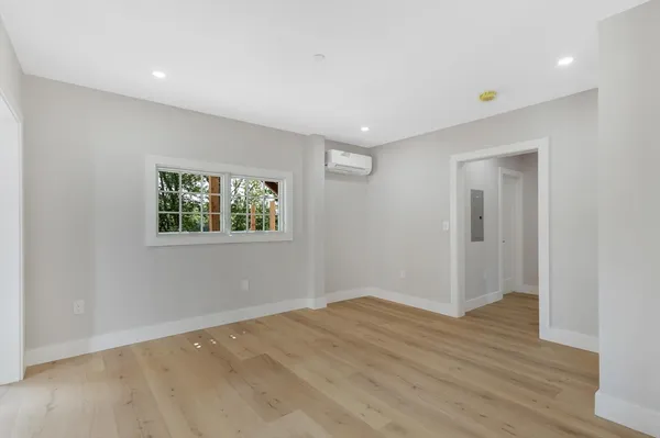 a view of an empty room with wooden floor and a window
