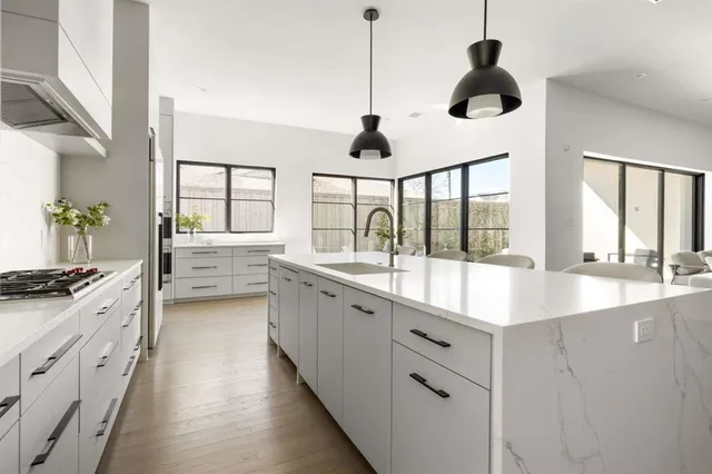 a large kitchen with kitchen island a large counter space a sink a window and stainless steel appliances