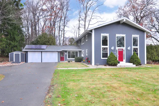 a view of a house with a yard and large tree