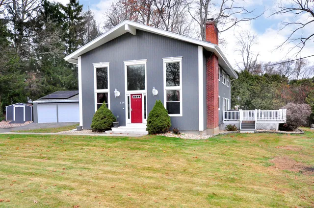 a view of a house with a yard potted plants and a large tree