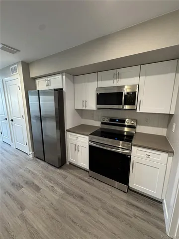 a kitchen with granite countertop a refrigerator and a stove top oven