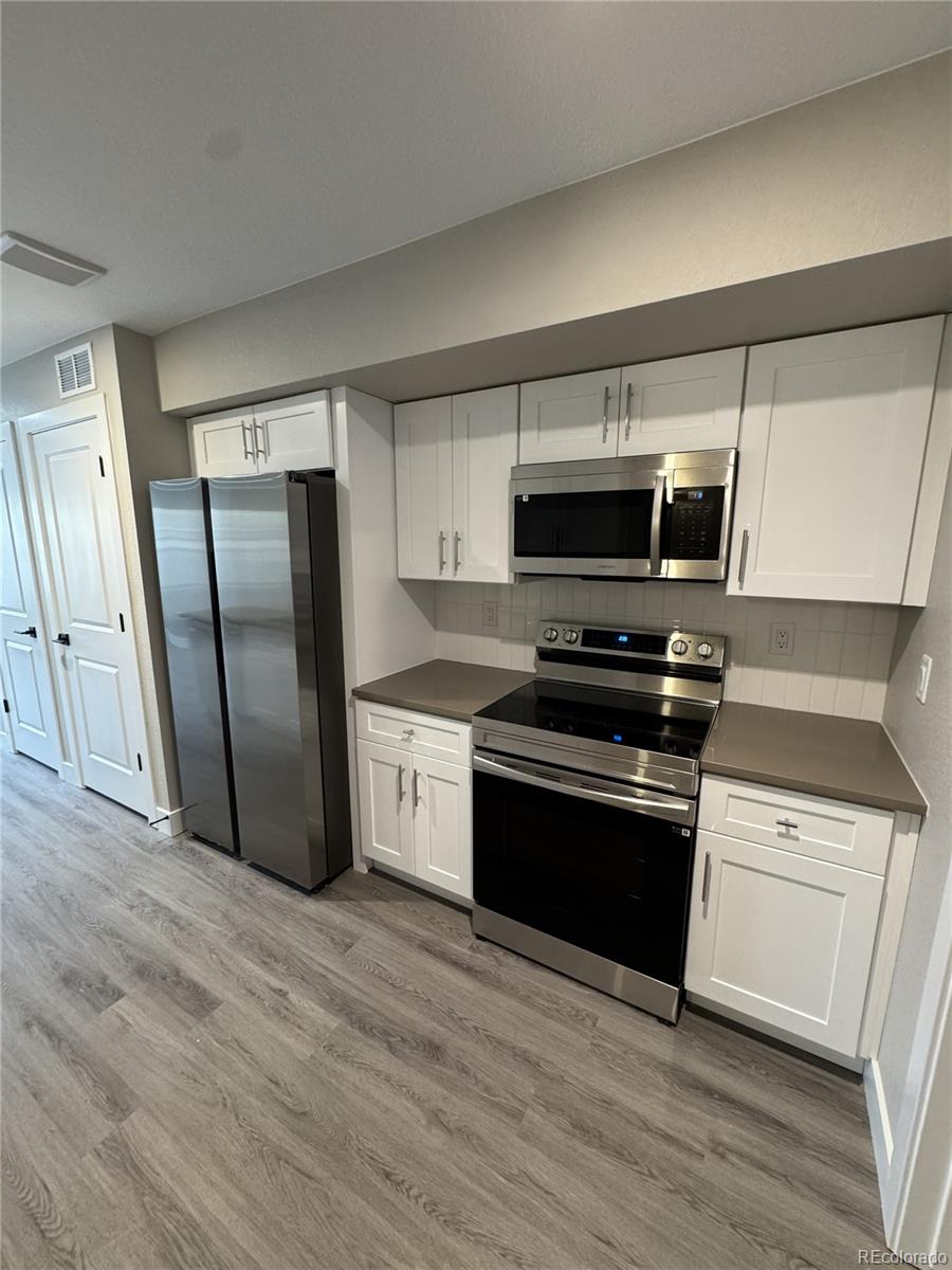 a kitchen with granite countertop a refrigerator and a stove top oven