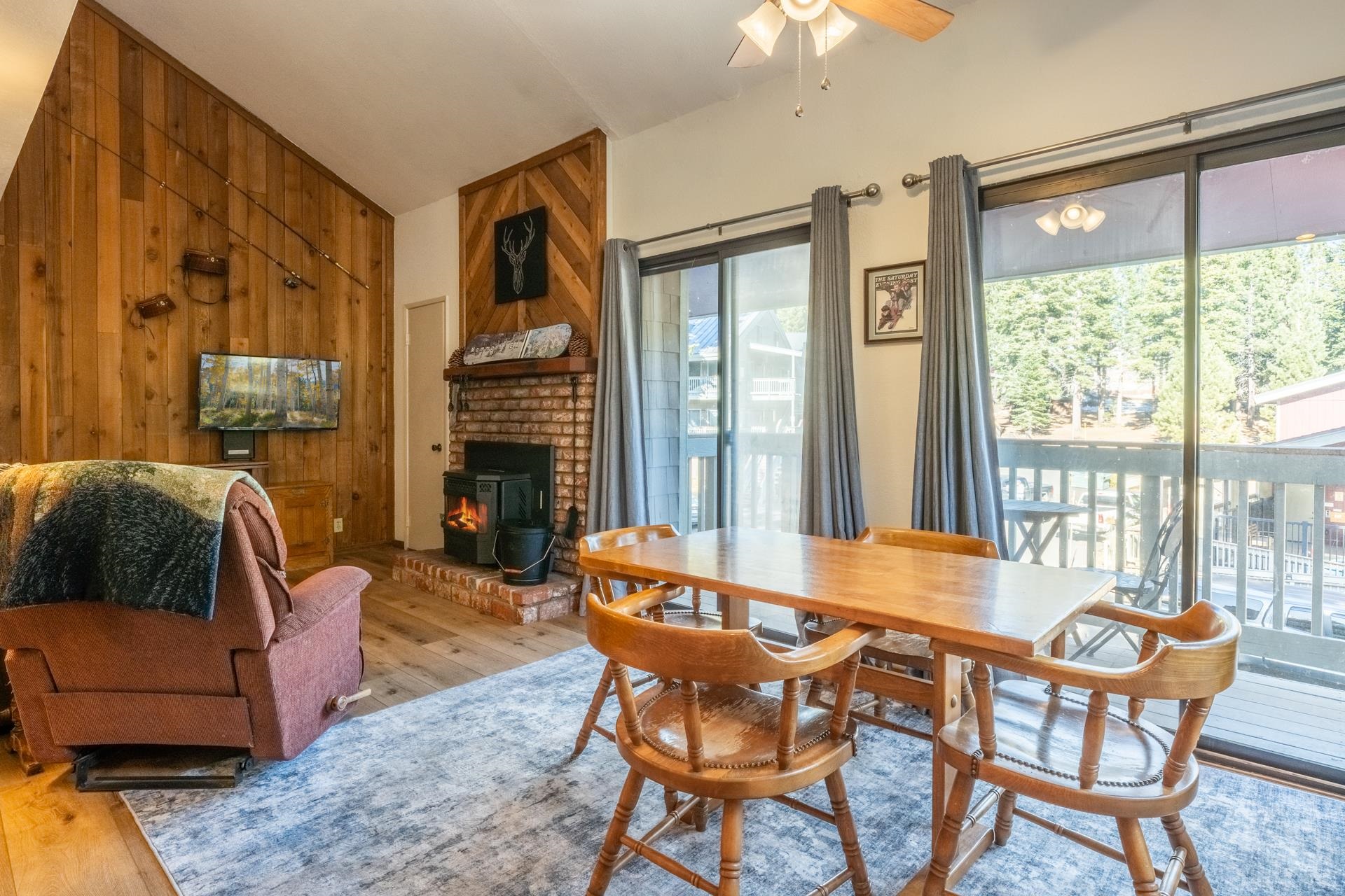 153 Lake Mary Road, Unit 132 Mammoth Lakes, CA 93546 - Photo 2 of 20 Dining area with hardwood / wood-style floors, a wood stove, wood walls, lofted ceiling, and a ceiling fan