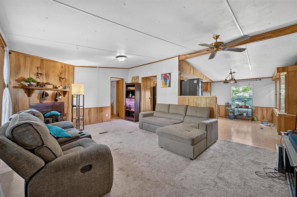 736 Little Joe Road Sanger, TX 76266 - Photo 3 of 17 Spacious living area featuring carpet flooring, wood-finish wall paneling, and a vaulted ceiling with exposed beams