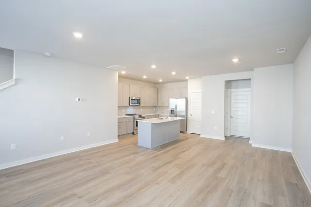 a view of kitchen with kitchen island wooden floor center island and stainless steel appliances