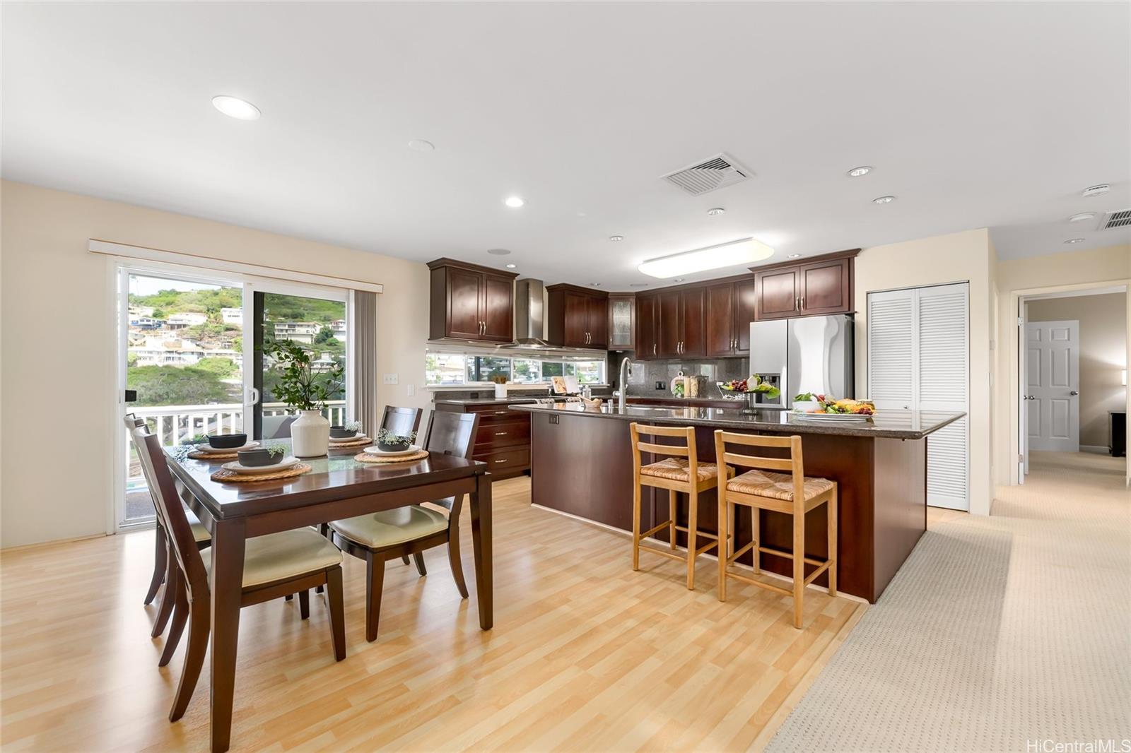 4562 Malia Street Honolulu, HI 96821 - Photo 11 of 25 a open dining room with stainless steel appliances kitchen island granite countertop a table and chairs with wooden floor