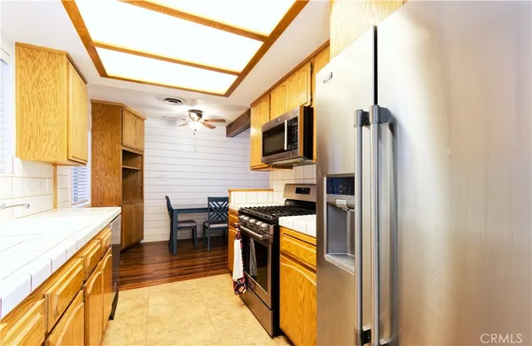 a kitchen with stainless steel appliances a stove top oven a sink a dining table and chairs