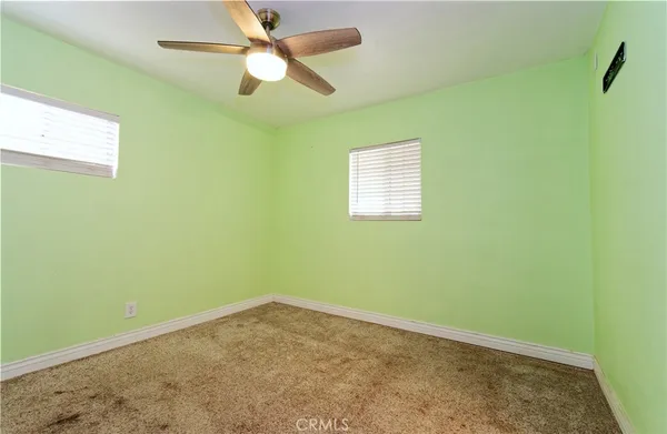 an empty room with a window and a fan