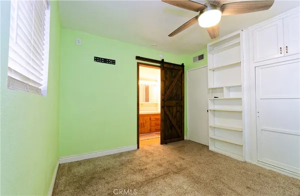a view of an empty room with closet and a window