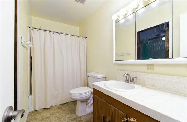 a bathroom with a granite countertop sink and a toilet