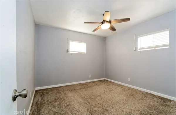 an empty room with ceiling fan and window