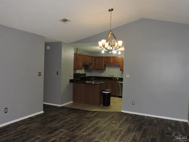 an empty room with wooden floor a refrigerator and kitchen view