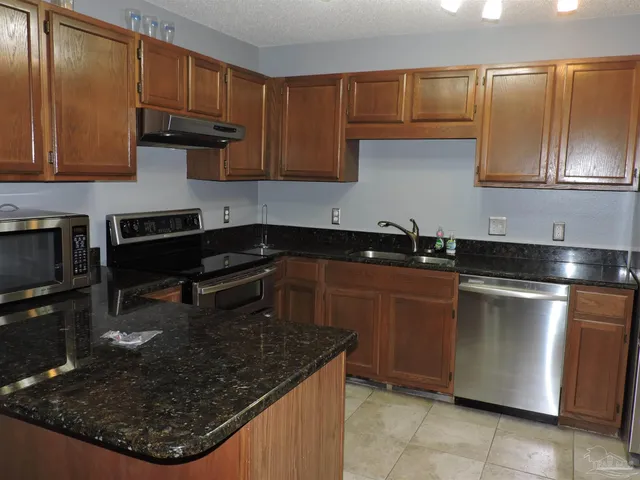 a kitchen with granite countertop wood cabinets and stainless steel appliances