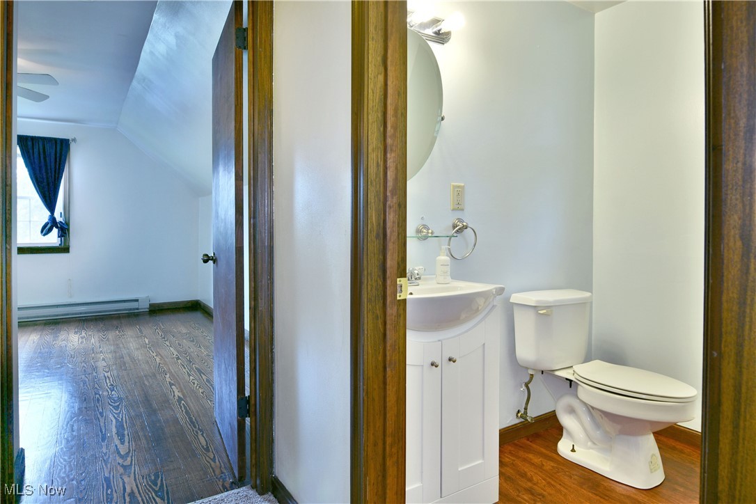 1141 Howell Road East Palestine, OH 44413 - Photo 35 of 41 Bathroom featuring dark wood-style floors, vanity, a baseboard radiator, vaulted ceiling, and ceiling fan
