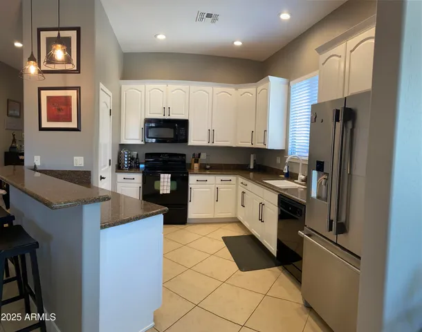 a kitchen with stainless steel appliances granite countertop a refrigerator a stove a sink and a microwave