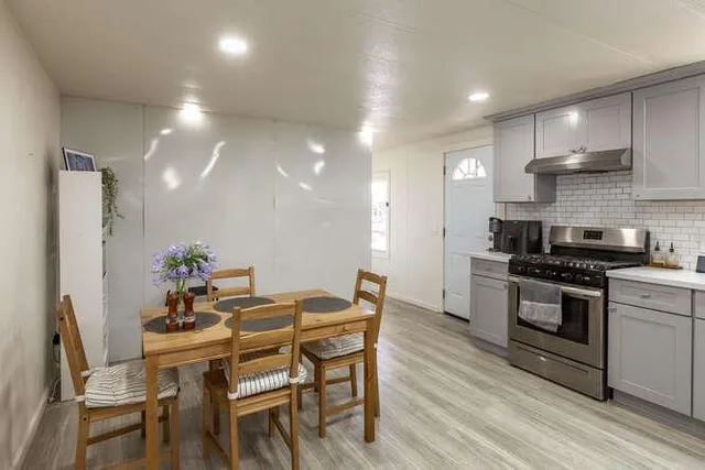 a kitchen with stainless steel appliances kitchen island granite countertop a stove a sink a refrigerator and a dining table