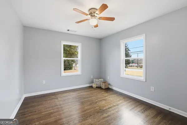 a view of an empty room with window and wooden floor