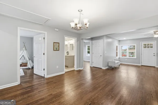 an empty room with wooden floor chandelier and windows