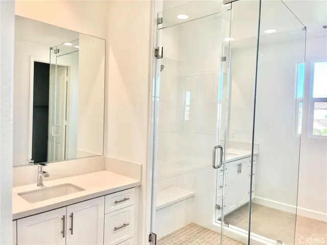 a bathroom with a granite countertop sink two mirror and a shower