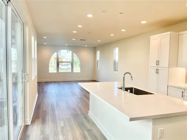 a view of a kitchen with kitchen island a sink wooden floor and a large window