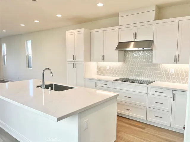 a kitchen with kitchen island granite countertop a sink and white cabinets