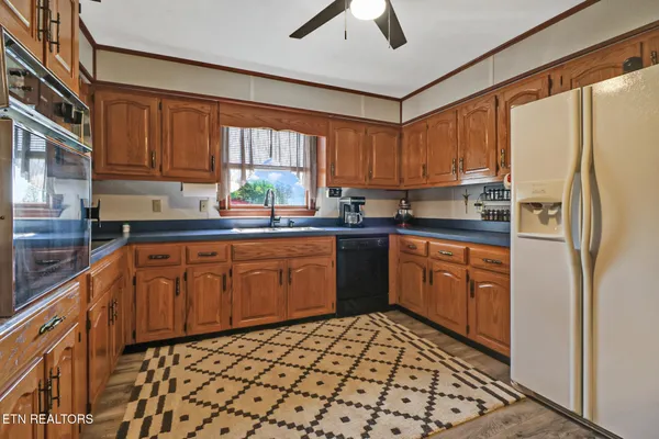 a kitchen with stainless steel appliances granite countertop a refrigerator a stove and a wooden cabinets