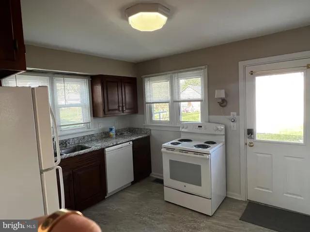 a kitchen with granite countertop a refrigerator stove top oven and sink