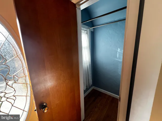 a view of an empty room with wooden floor fireplace and a window