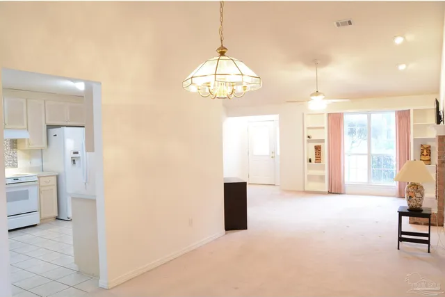 a view of an empty room and a kitchen with a sink