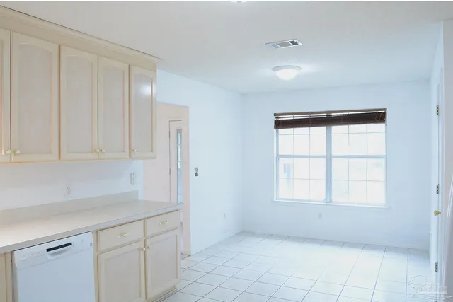 a kitchen with white cabinets and window