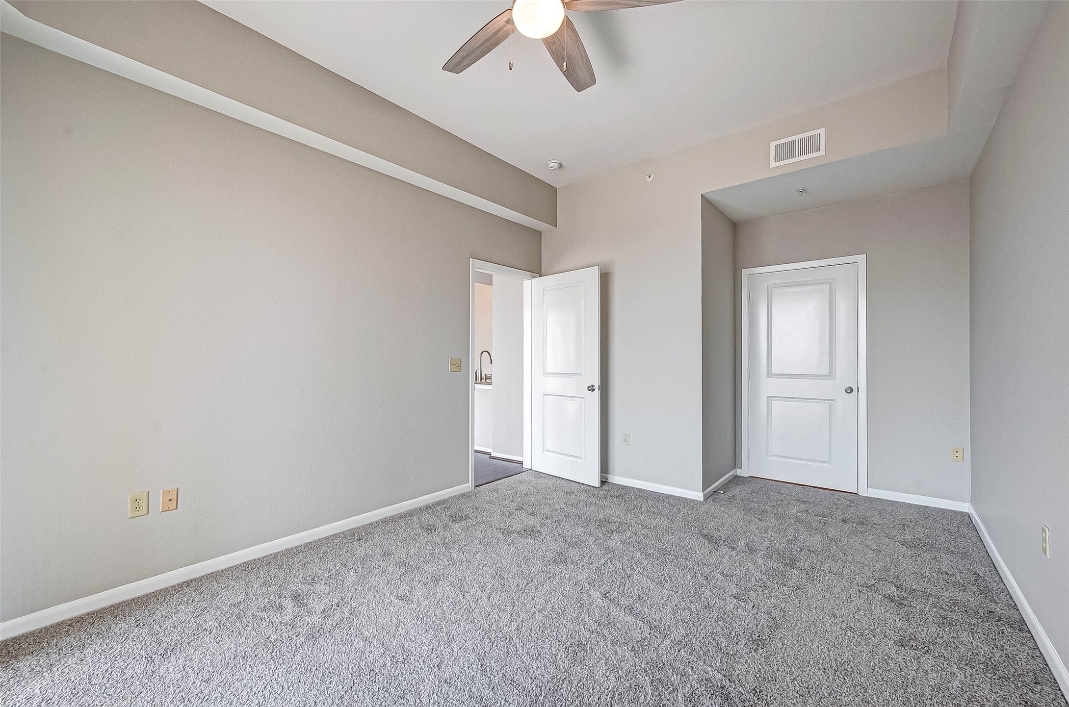 3505 Sage Road, Unit 2106 Houston, TX 77056 - Photo 19 of 31 This room features neutral gray walls, plush carpeting, and a ceiling fan. It has two doors, one leading to another space and one likely to a closet, offering a clean and modern feel, perfect for personalization.