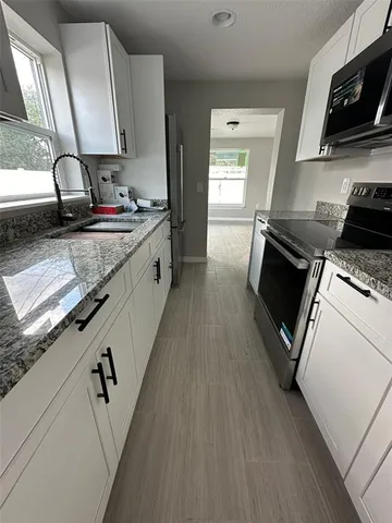 a kitchen with granite countertop a refrigerator stove sink and cabinets